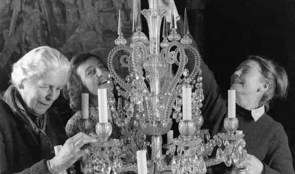 Historical photo of members of The Arts Society working on the preservation of a chandelier