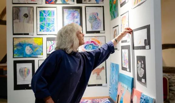 An Arts Society volunteer attaching artwork to a wall