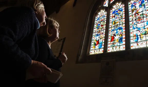 Photograph of two Arts Society Members admiring a stained glass window in a church