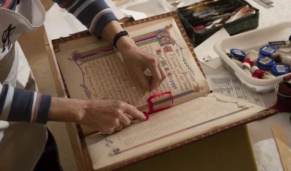 Photograph of the hands of an Arts Society Volunteer preserving a book