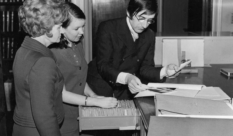 Historical photograph of early members of The Arts Society looking at records